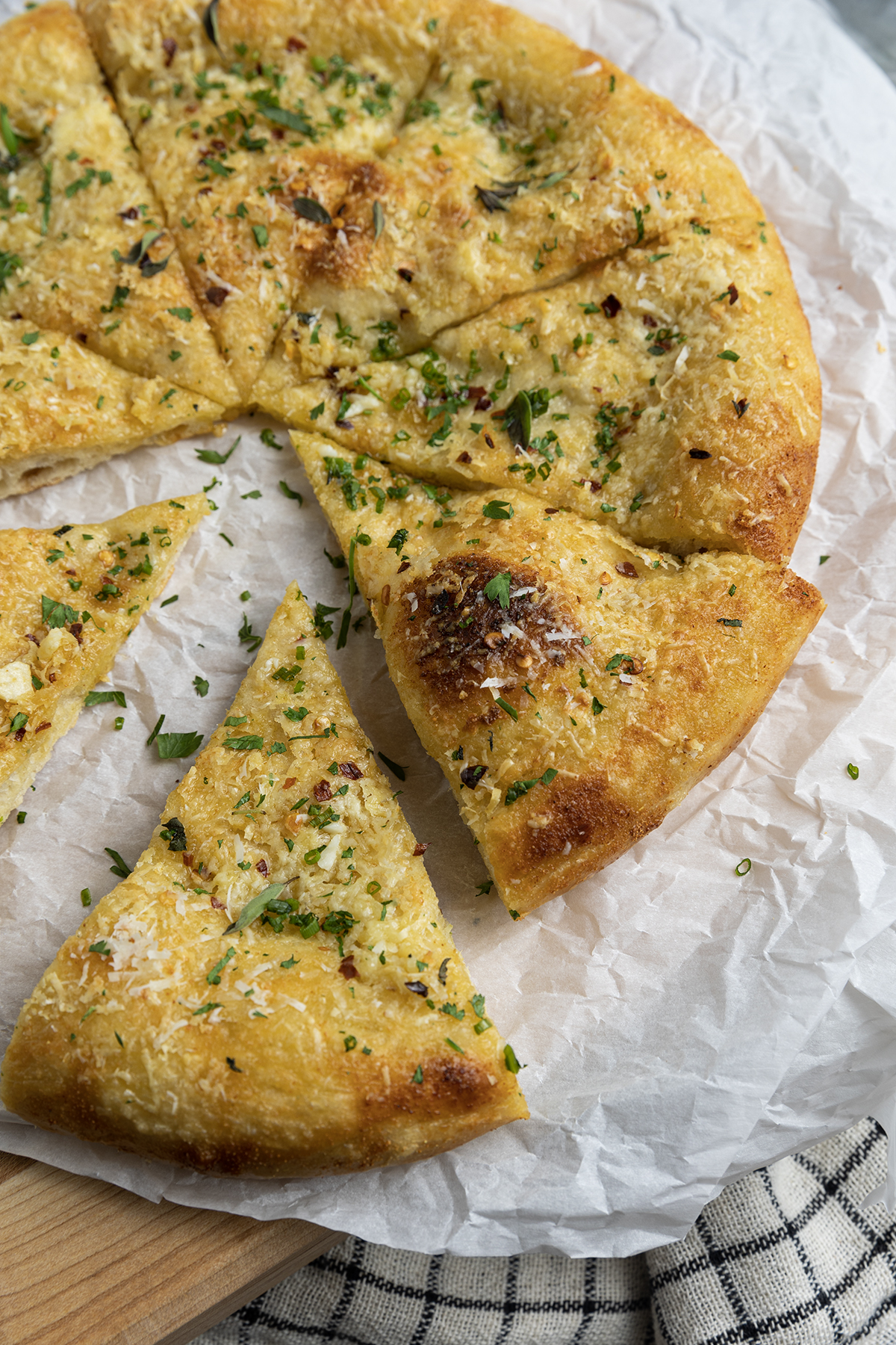 With its blistered, crispy crust and utterly irresistible aroma, Garlic Pizza is proof that the simplest things are often the best. You’ll find yourself turning to this deeply browned, super savoury pizza -made from simple ingredients that you likely have on hand already- more often than you can imagine. Garlic pizza is perfection in its simplicity. It’s just pizza dough brushed with homemade garlic oil, sprinkled with parmesan cheese, and a pinch of red pepper flakes.