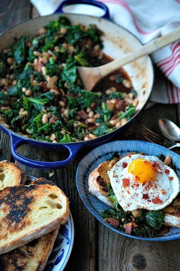 Teneri fagioli e verdure, cipolle caramellate, saporita pancetta, aglio a fette, paprika affumicata e un pizzico di spezie, sono i protagonisti di questo piatto unico, a basso costo, che piace alla gente, servito su fette di pane all'aglio croccante e tostato in padella.