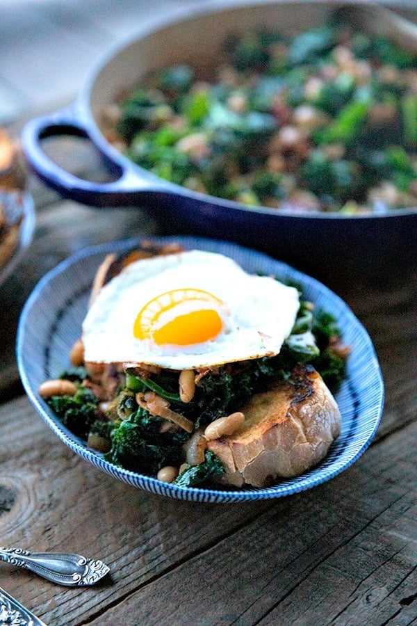 Teneri fagioli e verdure, cipolle caramellate, saporita pancetta, aglio affettato, paprika affumicata e un pizzico di spezie, sono i protagonisti di questo piatto unico, a basso costo, che piace alla gente, servito su fette di pane all'aglio croccante e tostato in padella.