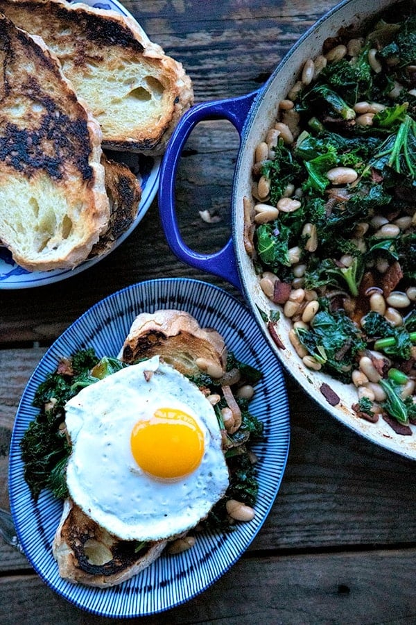 Feijões e verduras, cebolas caramelizadas, bacon salgado, alho fatiado, colorau fumado, e uma pitada de especiarias, estrela neste pão de um só prato, de baixo custo, servido sobre fatias indulgentemente grossas de pão de alho crocante e tostado.